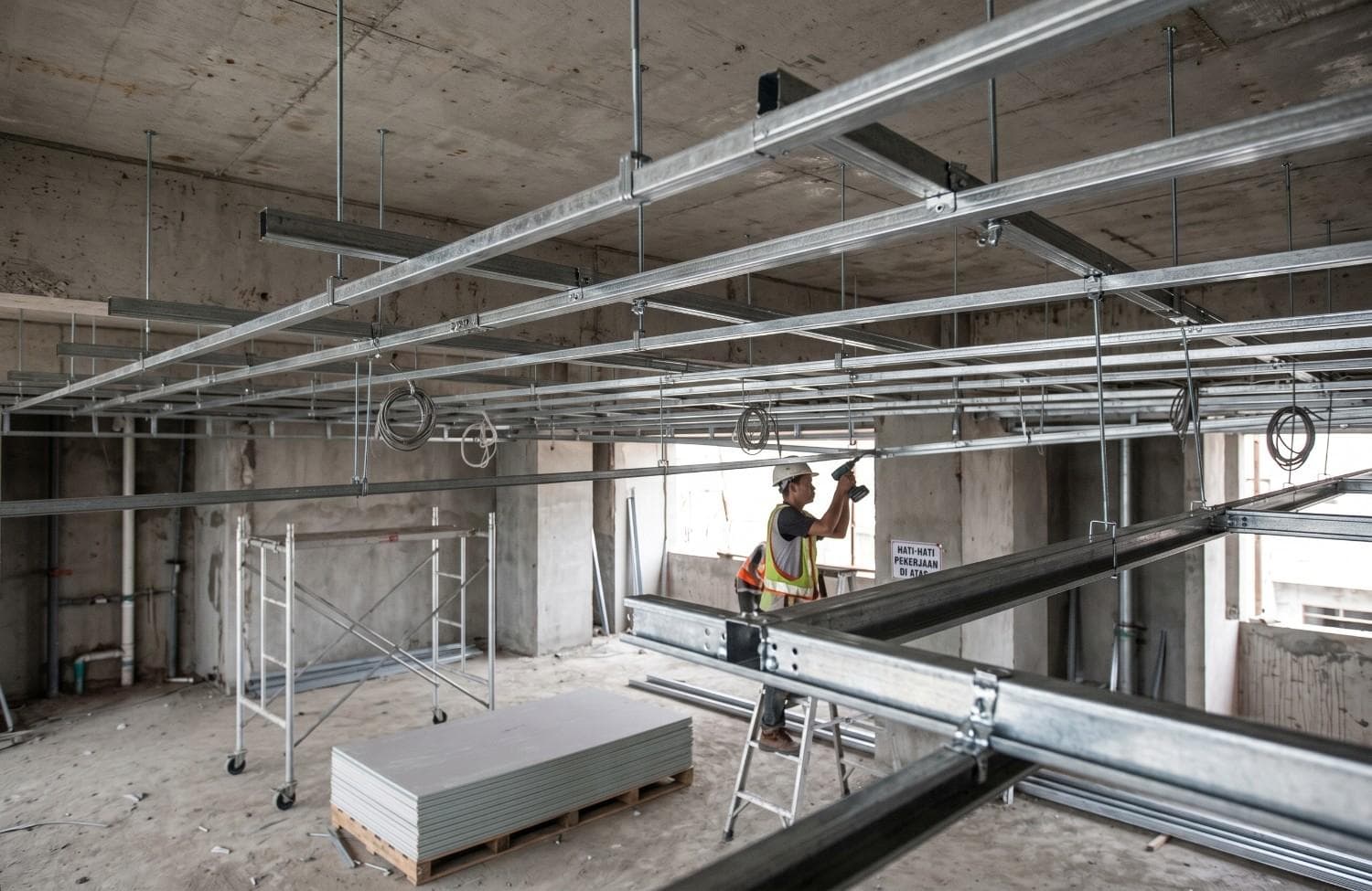 Pekerja konstruksi memasang bingkai plafon gipsum logam di situs interior