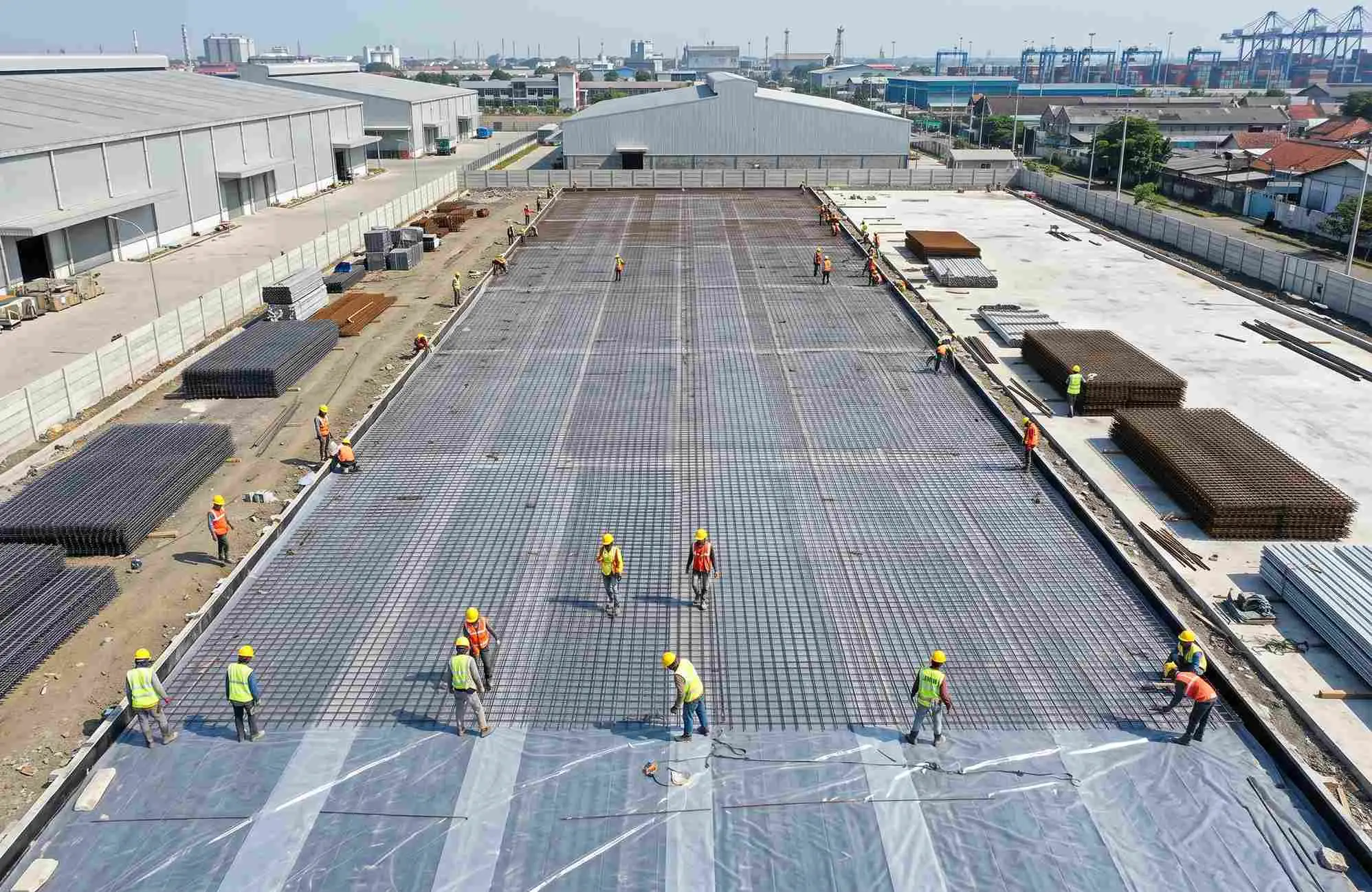 Pemasangan wiremesh M8 lembar di atas lapisan plastik cor untuk persiapan pengecoran lantai gudang logistik